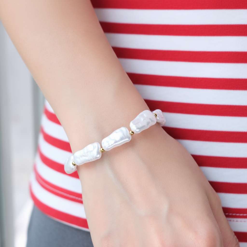 Bracelet Nausicaa avec perles blanches irrégulières et détails dorés porté au poignet.
