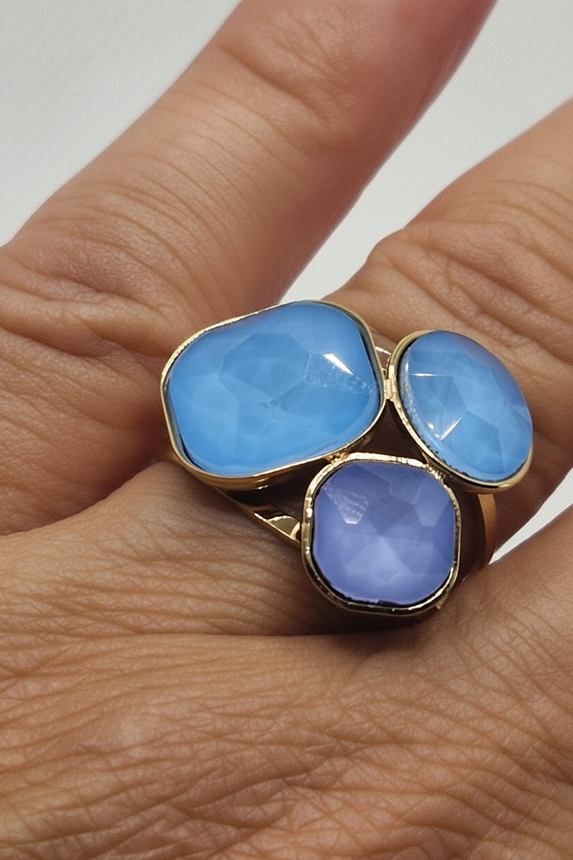 Bague Cyané dorée avec trois pierres bleues facettées en acier inoxydable.