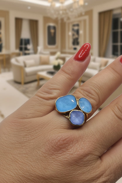 Bague Cyané dorée avec trois pierres bleues facettées en acier inoxydable.