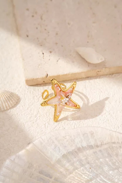 Bague étoile de mer Thétis dorée avec détails nacrés et reflets marbrés inspirés de l’océan.