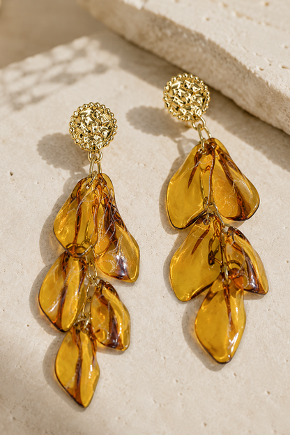 Boucles d'oreilles Éos Hatoria en acier inoxydable doré avec pétales ambrés translucides.