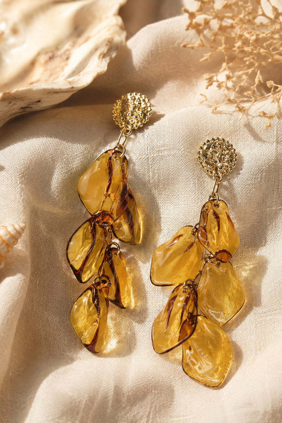 Boucles d'oreilles Éos Hatoria en acier inoxydable doré avec pétales ambrés translucides.