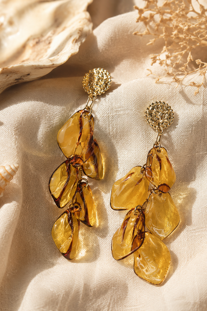 Boucles d'oreilles Éos Hatoria en acier inoxydable doré avec pétales ambrés translucides.