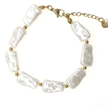 Bracelet Nausicaa avec perles blanches irrégulières et détails dorés porté au poignet.