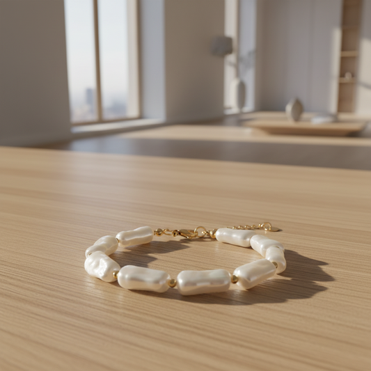 Bracelet Nausicaa avec perles blanches irrégulières et détails dorés porté au poignet.