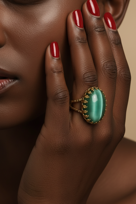 Bague Héméra portée à la main avec pierre ovale verte nacrée et contour doré.