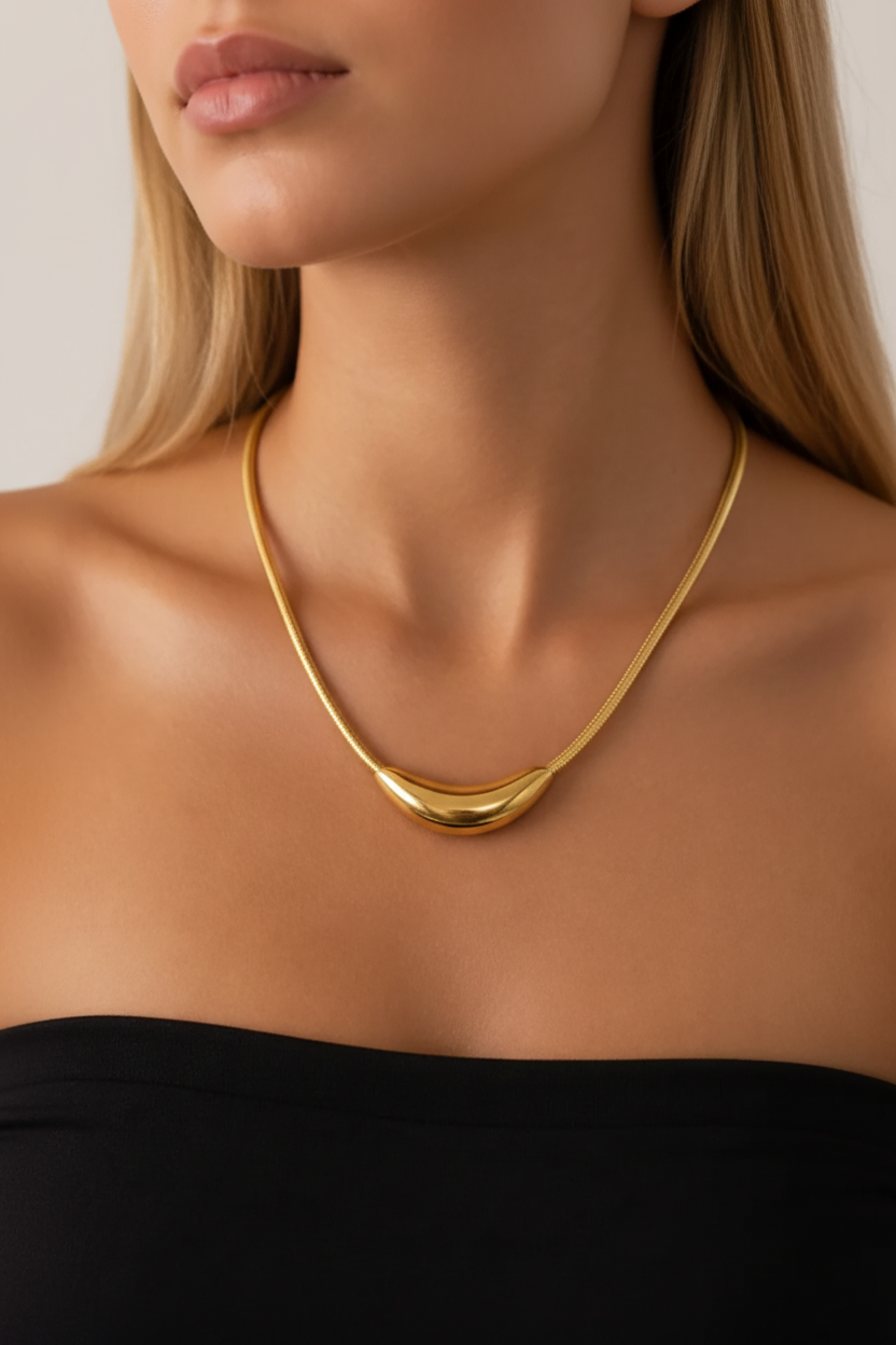 Collier Harmonia doré porté au cou avec pendentif courbe lisse et style minimaliste.