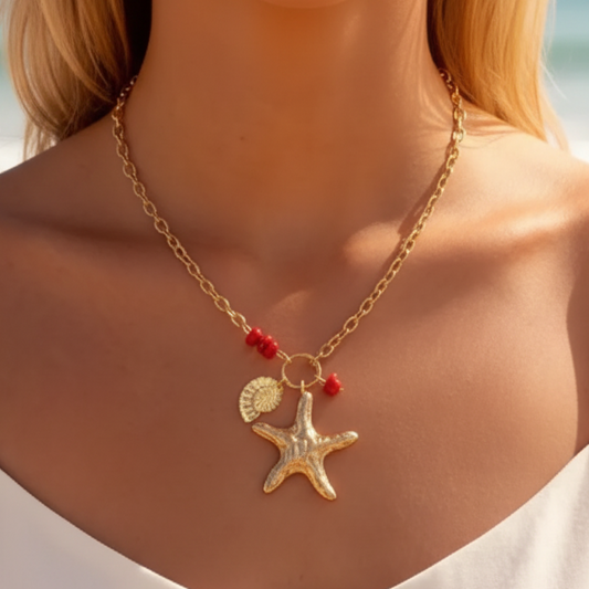 Collier Galatée doré avec pendentif étoile de mer et détails rouges porté au cou.