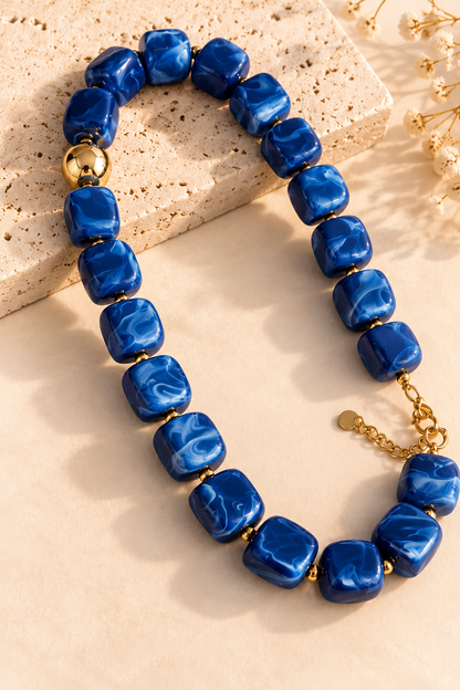 Gros plan des perles carrées en résine bleu marbré du collier AZURA