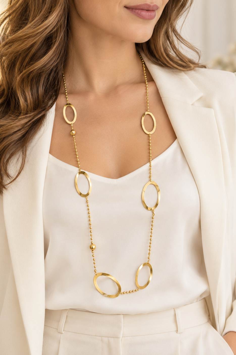 Collier long doré ORÉLIA porté sur une tenue écrue avec anneaux ovales