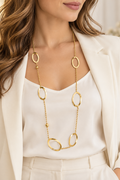 Collier long doré ORÉLIA porté sur une tenue écrue avec anneaux ovales